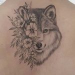 Tatuaggio da donna di un lupo con fiori sulla schiena