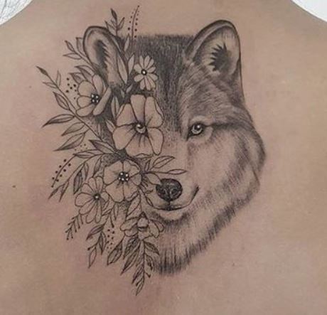 Tatuaggio da donna di un lupo con fiori sulla schiena