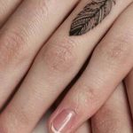 Piccola piuma tatuata sulle dita della mano