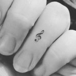 Piccolo tatuaggio chiave musicale sulle dita