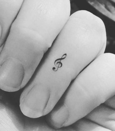 Piccolo tatuaggio chiave musicale sulle dita