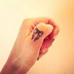 Tatuaggio piccolo fiocco sulle dita