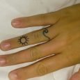 Piccolo tatuaggio sul dito onda con sole