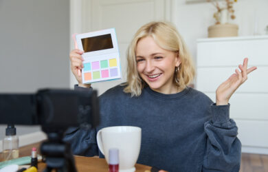 Portrait of beautiful lifestyle blogger, girl records a video on her camera for social media, shows palette of eyeshadows, does a makeup tutorial for her followers, sits in her room